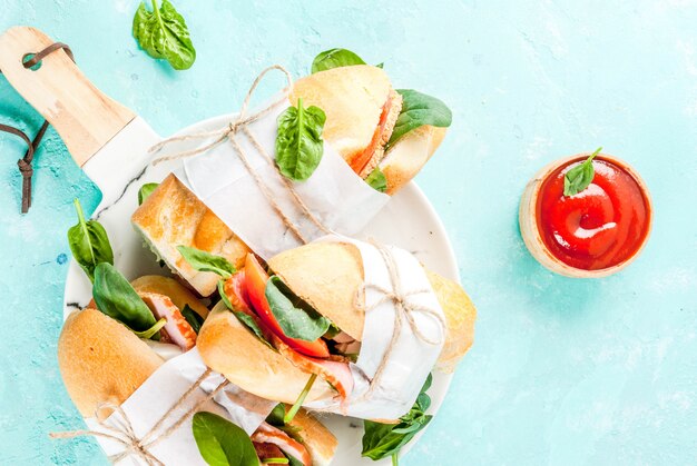 Frisches Stangenbrotsandwich mit Speckkäsetomaten und hellblauem Hintergrund des Spinats