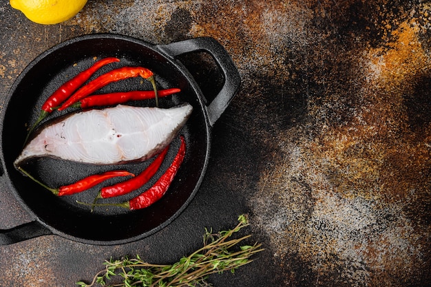 Frisches Steak roher Fisch Heilbutt Set, mit Zutaten und Rosmarinkräutern, auf altem dunklen rustikalen Tischhintergrund, Draufsicht flach, mit Kopierraum für Text