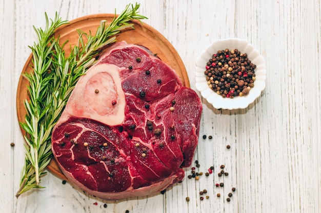 Frisches Stück Fleisch großes Rindersteak am Knochen Ossobuco mit Pfeffer-Rosmarin auf dem Brett