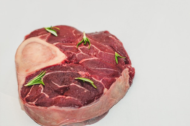 Frisches Stück Fleisch großes Rindersteak am Knochen Ossobuco mit Rosmarinzweig