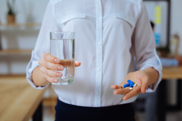 Frisches Wasser. Ernsthafter Büroangestellter, der Glas in der rechten Hand hält und schicke Kleidung trägt, während er Sie behandelt