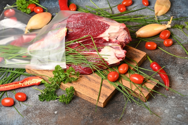 Frischfleisch mit Bestandteilen für das Kochen auf braunem hölzernem Schneidebrett.