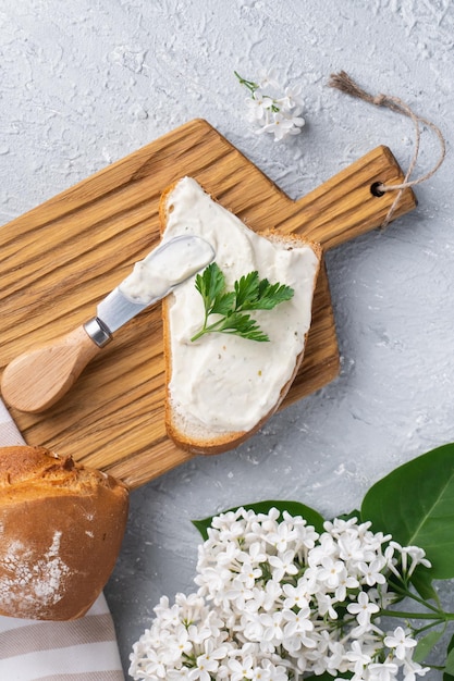 Foto frischkäse mit kräutern und gewürzen auf einer scheibe frischem, knusprigem roggenbrot mit käsemesser in der nähe