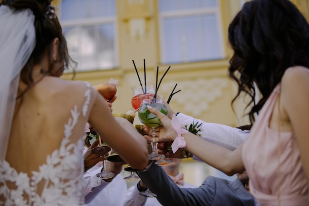 frischvermählte mit gästen bei der hochzeit stoßen an, nahaufnahme von hände mit brille. Prost. Hochzeit