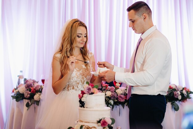 Frischvermählte schneiden, lachen und probieren glücklich die Hochzeitstorte