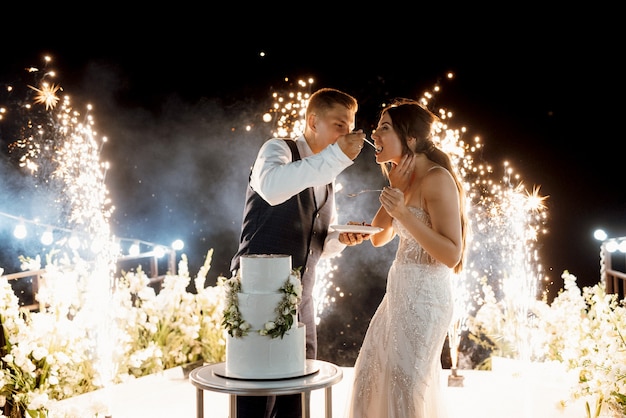 Frischvermählte schneiden, lachen und probieren glücklich die Hochzeitstorte