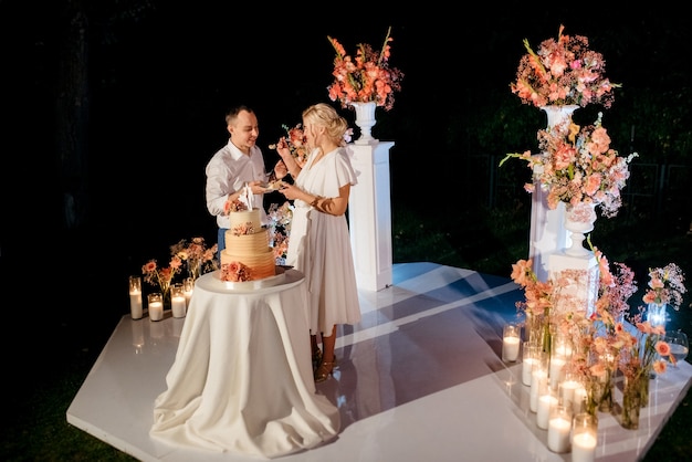 Frischvermählte schneiden, lachen und probieren glücklich die Hochzeitstorte