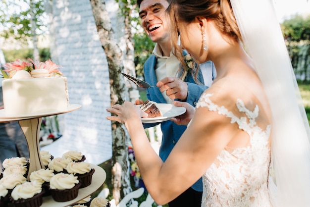 Frischvermählte schneiden, lachen und probieren glücklich die Hochzeitstorte