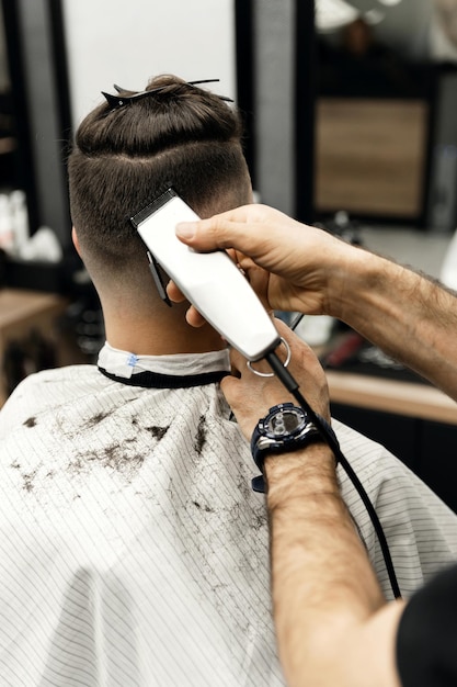 Friseur dabei, einen Kunden in einem Friseursalon mit einer Schere in einem Schönheitssalon zu schneiden