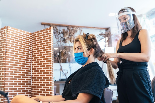 Friseur, der die Haare einer Frau bügelt