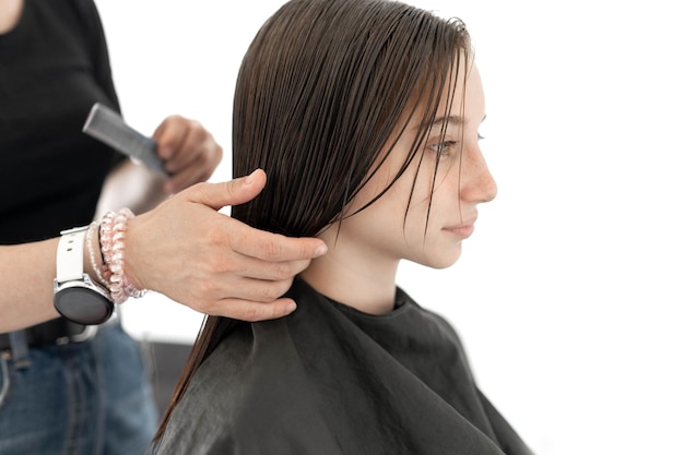 Friseur, der Haare des Mädchens für Haarschnitt weibliches Kind im Schönheitssalon vorbereitet