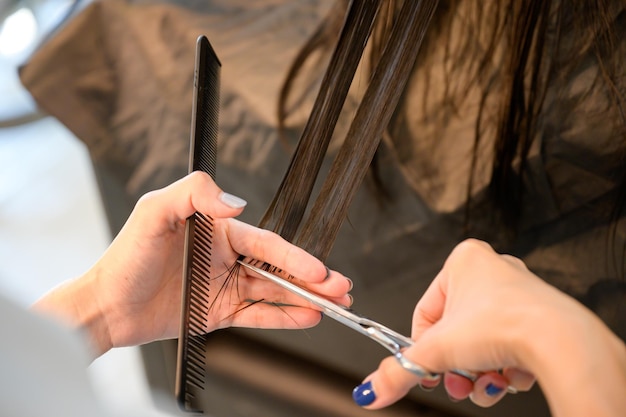 Friseur, der Haare für junge Kundinnen mit einer Schere schneidet, um Haare in einem Schönheitssalon zu schneiden