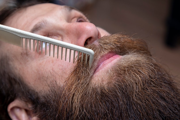 Friseur, der im Friseursalon roten Bart kämmt.