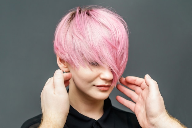 Friseur, der weibliches rosa Haar prüft