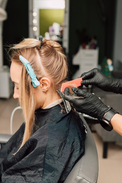 Friseur färbt einem Kunden in schwarzen Handschuhen Haarsträhnen