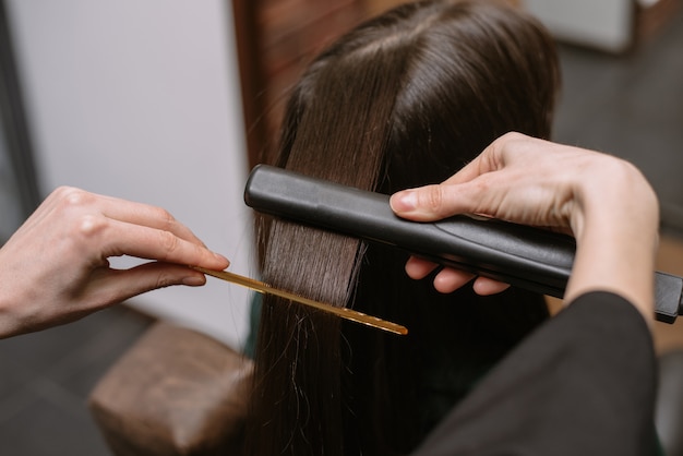 Friseur glättet die Haare eines Kunden