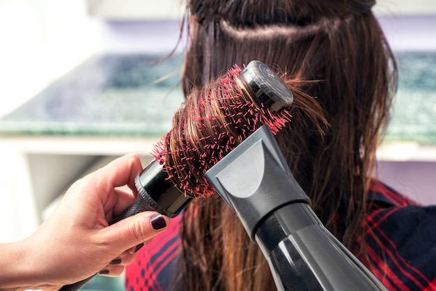 Friseur Haare bürsten mit einem Haartrockner