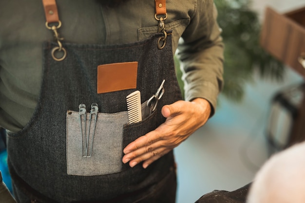 Friseur in der Schürze mit Werkzeugen für Haarschnitt