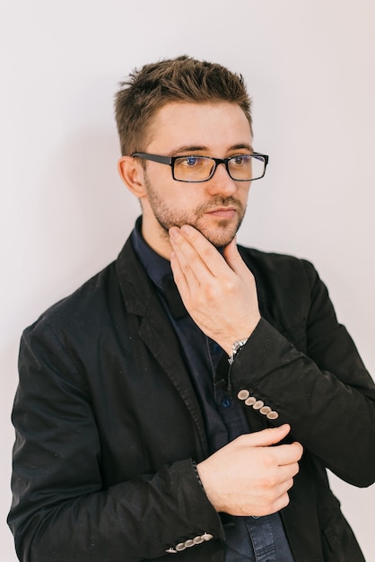 Friseur in schwarzer Jacke und blauem Hemd berührt sein Gesicht mit der Hand.