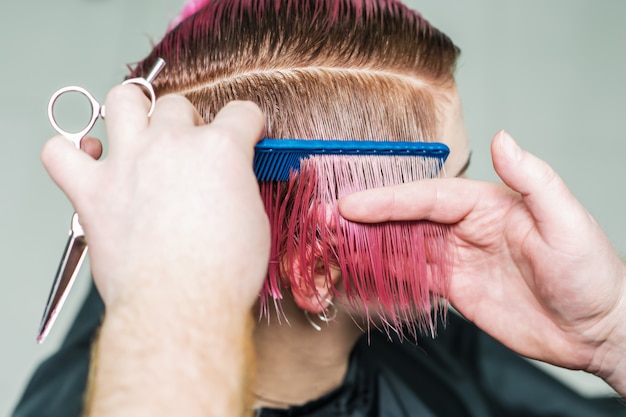 Friseur kämmt rosa kurzes Haar.