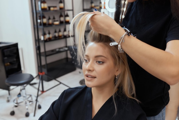 Friseur macht Bouffant mit Kamm auf dünnen Strähnen. Shatush-Technik zur Haaraufhellung.