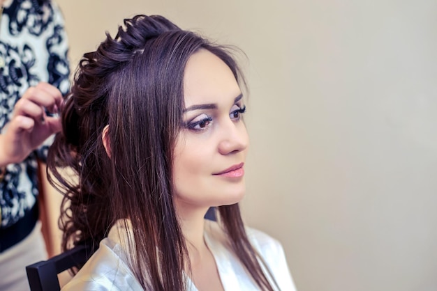 Friseur macht der Braut schöne Frisur für langes Haar am Morgen der Hochzeit