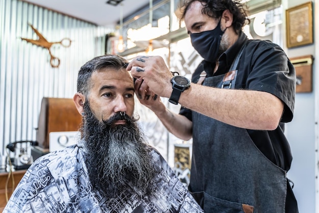 Friseur mit Maske, der mit einem Kunden arbeitet