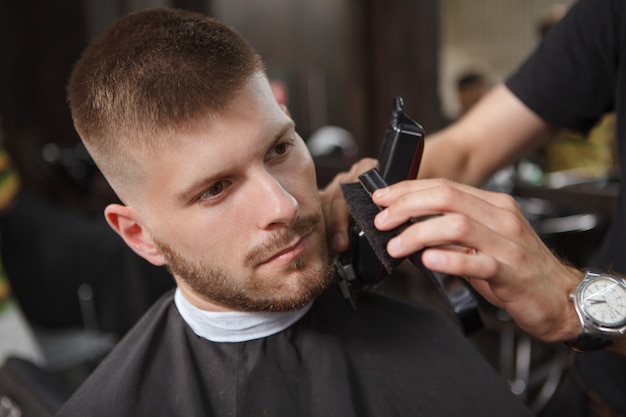 Friseur rasiert einen Kunden im Salon