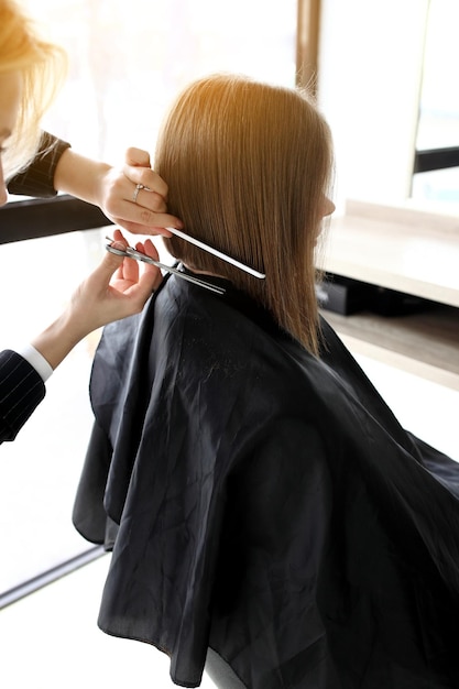 Friseur schneidet braunes Haar mit einer Schere
