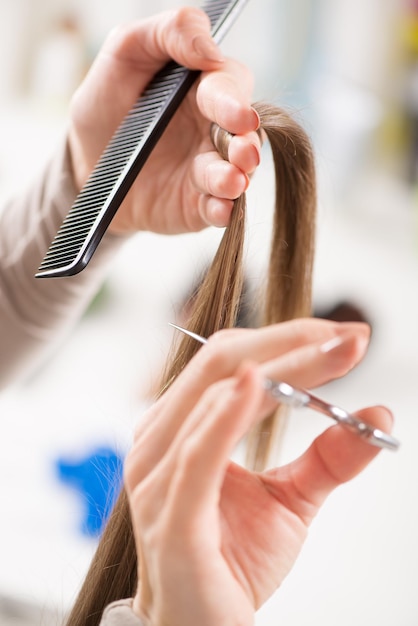 Friseur schneidet Haare einer Frau.