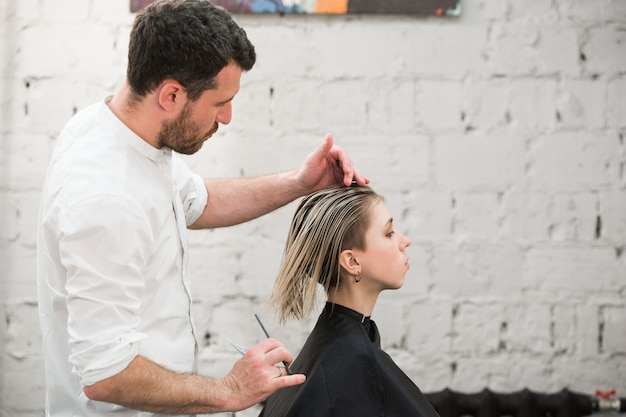 Friseur schneidet Haare mit einer Schere im professionellen Friseursalon