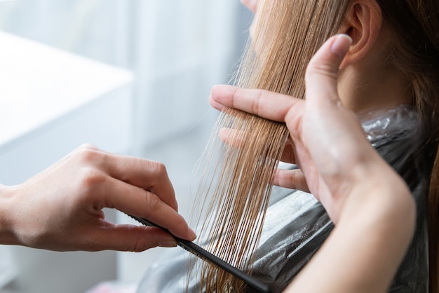 Friseur schnitt Haare einer blonden jungen Frau im Friseursalon