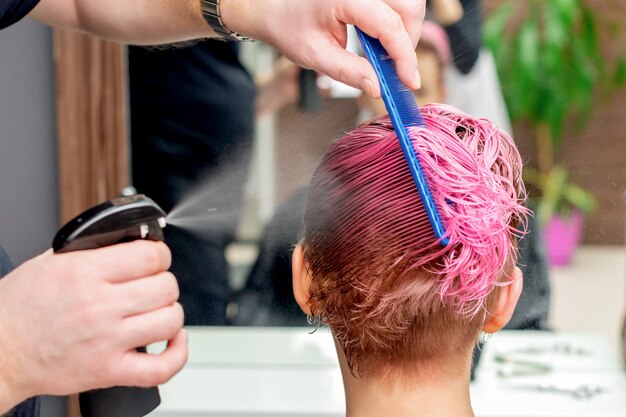 Friseur streut Wasser auf die Haare.