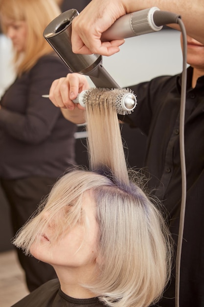 Friseur Styling Kundenhaar mit Haartrockner und Rundbürste