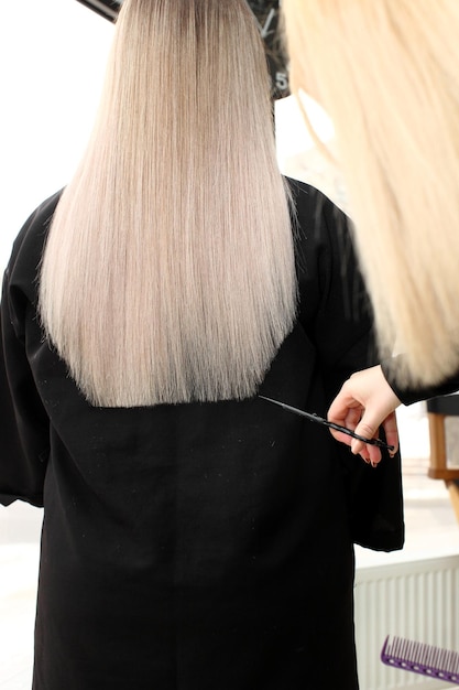 Friseur trimmt blondes Haar mit einer Schere