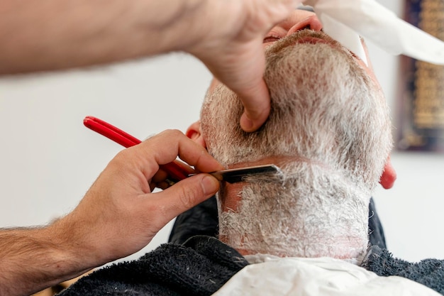 Friseur trimmt und schneidet bärtigen Mann mit Rasiermaschine im Friseursalon Hairstyling-Prozess