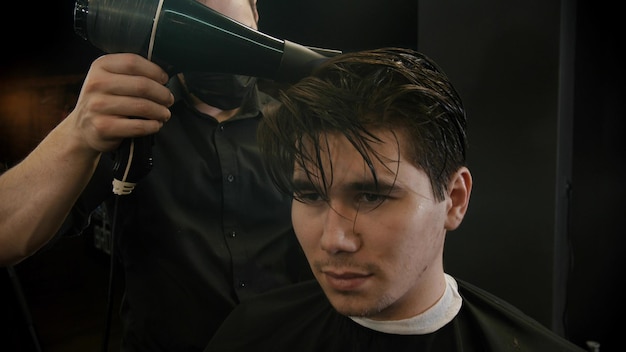 Friseur trocknet die Haare seines nassen Kunden