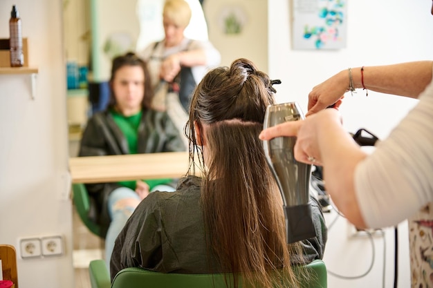 Friseur trocknet und stylt die Haare mit einem Haartrockner im Schönheitssalon