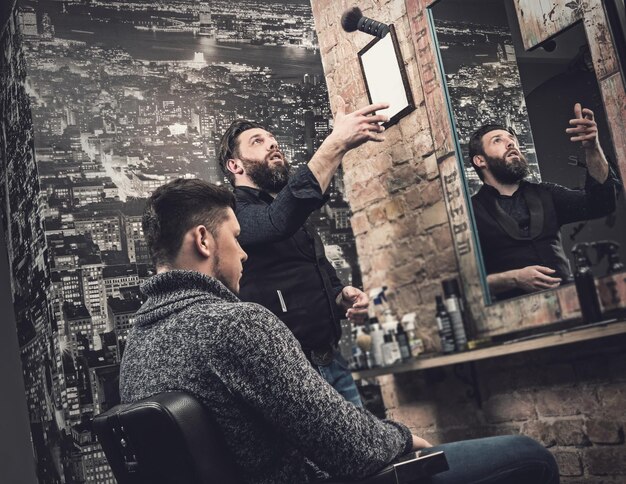 Friseur während seiner Arbeit mit einem Kunden in seinem Studio