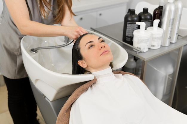 Friseur wäscht die Haare eines jungen brünetten Mädchens vor einem Haarschnitt in einem modernen Schönheitssalon