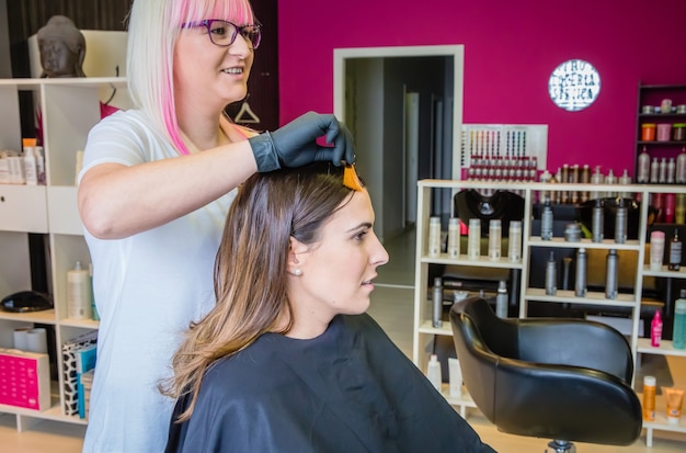 Friseur zeigt der schönen jungen Frau eine Haarfärbeprobe, bevor sie ihre Haarfarbe ändert