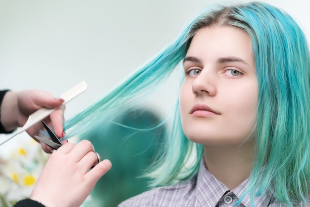 Friseurausschnitt mit Scheren langes grünes Haar der jungen Frau. Haarpflege im professionellen Schönheitssalon.