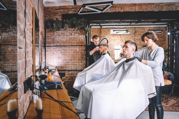 Friseure schneiden ihre Kunden im Barbershop. Werbe- und Friseurkonzept