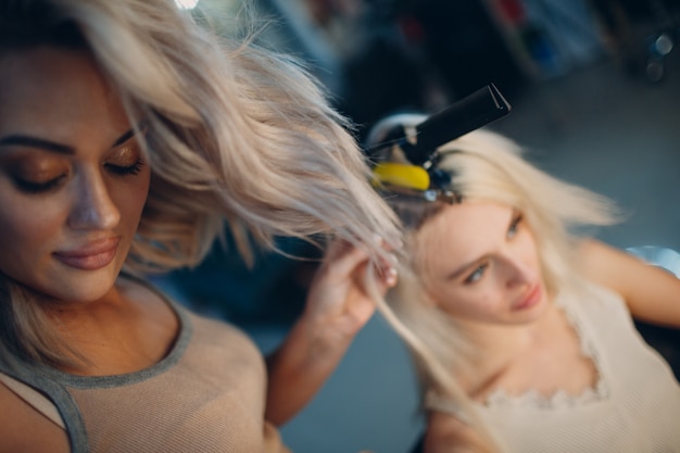 Friseurfrau, die junge Frau mit blonden Haaren im Schönheitssalon Haarverlängerungen macht. Professionelle Haarverlängerung.