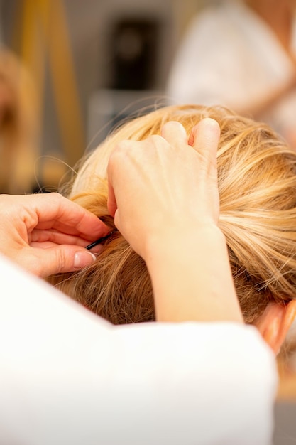 Friseurhände machen professionelles Haarstyling von weiblichen langen Haaren in einem Schönheitssalon