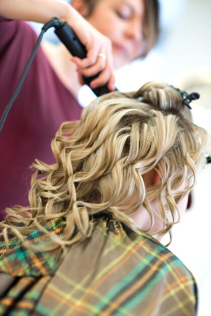 Foto friseurin benutzt ausrüstung für blonde braut im friseursalon