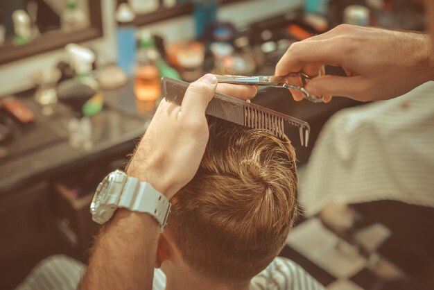 Friseurladen. Nahaufnahme des Mannhaarschnitts, Meister macht das Haarstyling im Friseurladen. Getönte Vintage-Fotos.