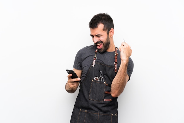 Friseurmann in einem Schutzblech mit Telefon in Siegposition