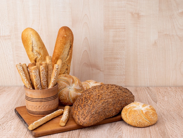 ƒRisp-Brot mit Brötchen. Französische Baguettes. Frisches Knäckebrot. Brot Hintergrund. Unterschiedliche Rasse auf hölzernem Hintergrund.