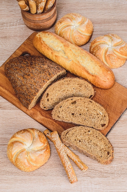 ƒRisp-Brot mit Brötchen. Französische Baguettes. Frisches Knäckebrot. Brot Hintergrund. Unterschiedliche Rasse auf hölzernem Hintergrund.